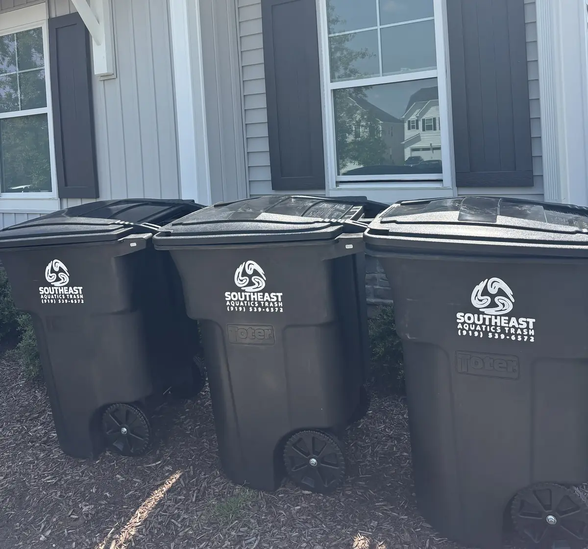 Three Southeast Aquatics Trash carts beside a home